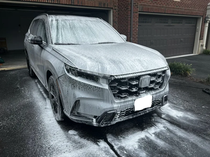 Volkswagen SUV covered in cleaning foam during an exterior wash in a driveway